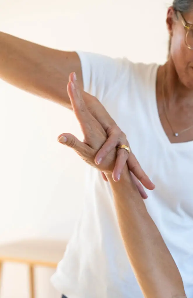 Das Bild zeigt den kinesiologischen Muskeltest. Eine Frau übt mit der Hand leichten Druck auf den ausgestreckten Arm einer zweiten Person aus.
