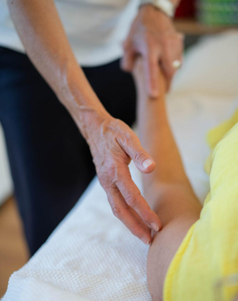 Eine Detailaufnahme einer Hand die den Arm einer Person abtastet.